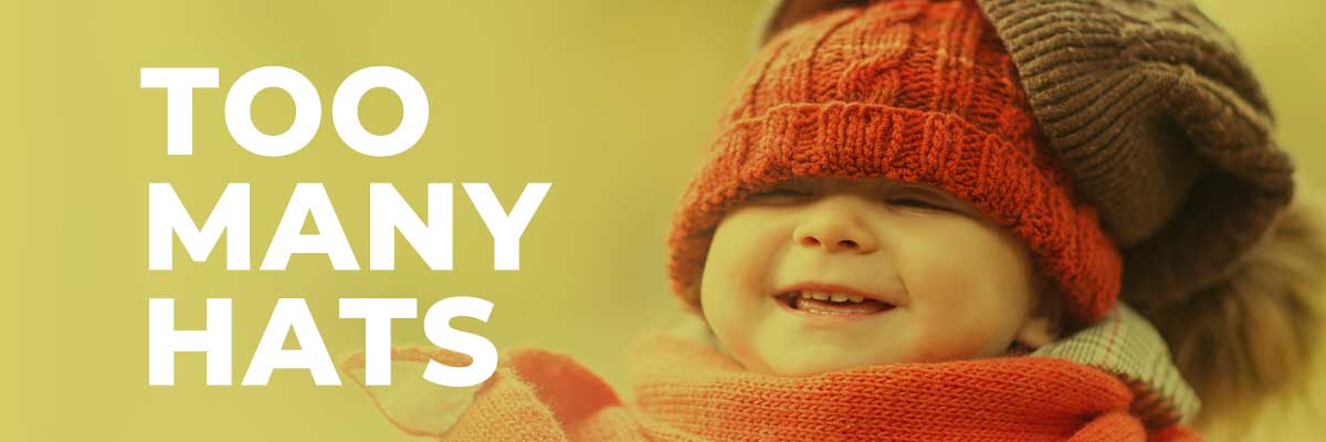 Aug-Newsletter Too Many Hats Text on Photo of Baby Wearing Mutliple Hats